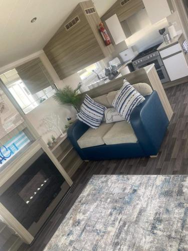 a living room with a blue couch and a fireplace at CARAVAN NEL in Meliden