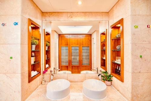 a bathroom with two sinks and two mirrors at Golden Beachside Resort Danang in Da Nang