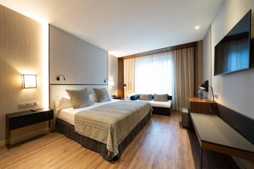 a hotel room with a bed and a couch at Catalonia Barcelona Plaza in Barcelona
