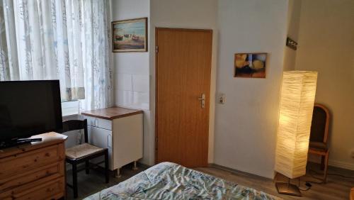 1 dormitorio con 1 cama, TV y puerta en Hügel en Bad Wildungen