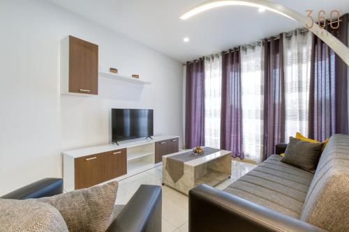 ein Wohnzimmer mit einem Sofa und einem TV in der Unterkunft Beautiful 3BR Apt with Panoramic Terrace in Qawra by 360 Estates in St Paul's Bay
