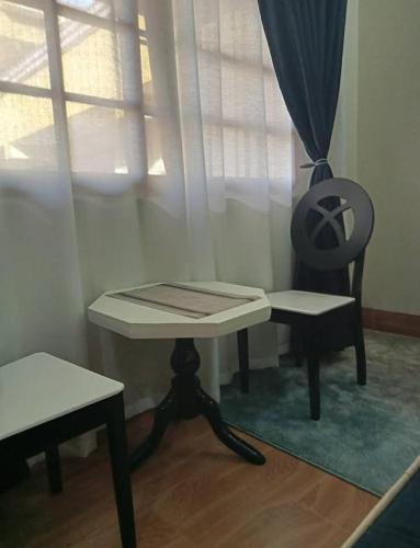 a table and a chair in a room with a window at Riverside Apartments in Buwate