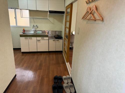 a kitchen with white cabinets and a bunch of shoes on the floor at OKAERI築地町 in Takamatsu