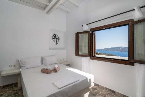 a white bedroom with a bed with a window at Noula House & Studios in Plaka Milou