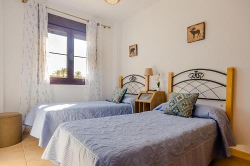 a bedroom with two beds and a window at Smart La Barrosa in Novo Sancti Petri