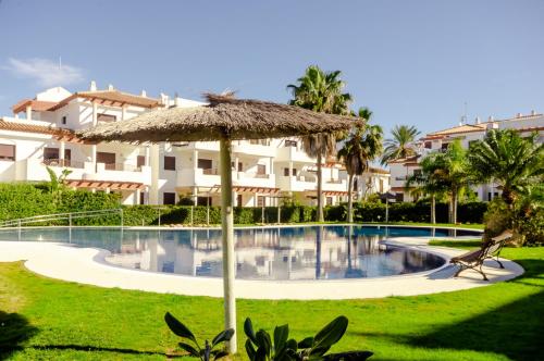 a resort with a swimming pool and a straw umbrella at Smart La Barrosa in Novo Sancti Petri