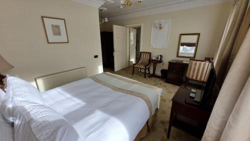 a bedroom with a white bed and a desk and chair at Botleigh Grange Hotel & Spa in Southampton