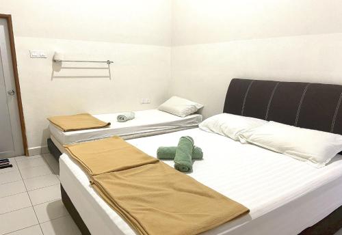 two beds in a room with towels on them at OYO 90971 Pollock Homestay in Sungai Lembing