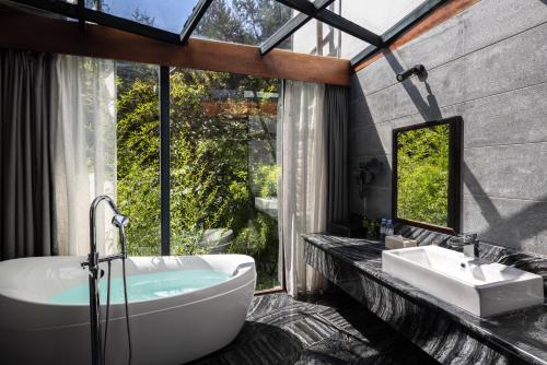 a bathroom with a tub and a sink and a window at 音糖Museum雪山森系隐奢艺术庄园 丽江束河古镇店 in Lijiang