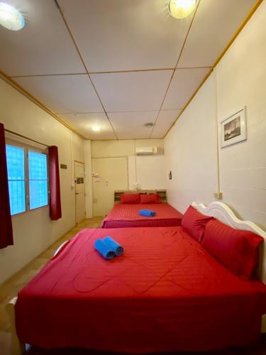 two beds in a room with red sheets and pillows at Plaza Huahin in Hua Hin