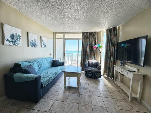a living room with a blue couch and a tv at Ocean Front Comfort 1BR Condo Atlantica in Myrtle Beach