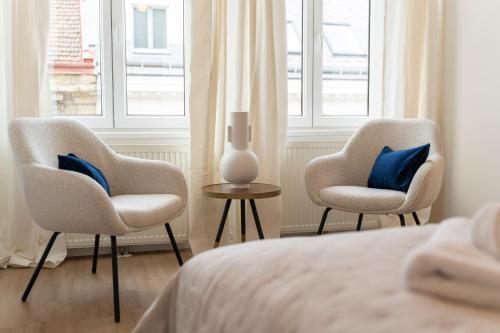 2 Stühle und eine Vase auf einem Tisch im Schlafzimmer in der Unterkunft Ludwig Apartment I levestate in Wien