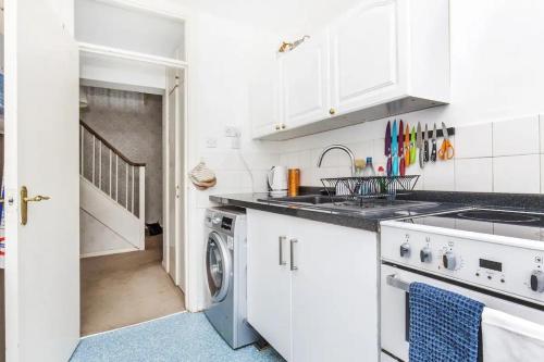 a white kitchen with a sink and a dishwasher at Pass the Keys - Beautiful Flat with balcony in Swiss Cottage, London in London