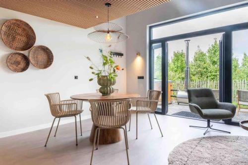 a dining room with a table and chairs and a glass door at Casa Fico, luxe huisje met hottub én kamado in Kapelle