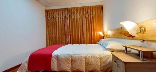 ein Schlafzimmer mit einem Bett und einem Schreibtisch mit einer Lampe in der Unterkunft Eden Lodge in Cabanaconde