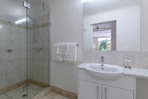 ein weißes Bad mit einem Waschbecken und einer Dusche in der Unterkunft 1 Bedroom @ Palm Villas #3 in Port Douglas