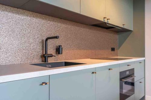 a kitchen with white cabinets and a sink at Casa Fico, luxe huisje met hottub én kamado in Kapelle