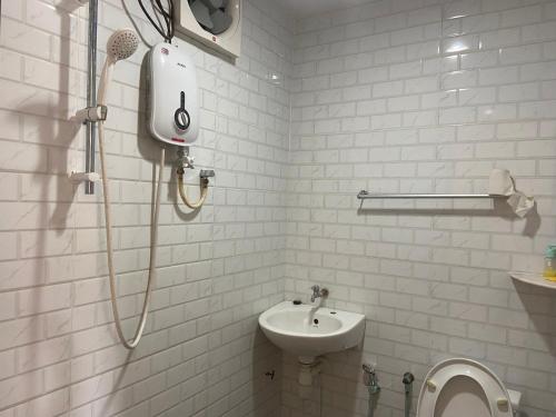 a white bathroom with a shower and a sink at OYO 90971 Pollock Homestay in Sungai Lembing
