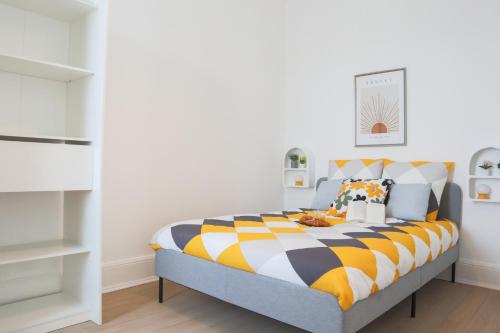 - une chambre avec un lit et une couette jaune et blanche dans l'établissement LE FUNNY, Mulhouse centre, à Mulhouse