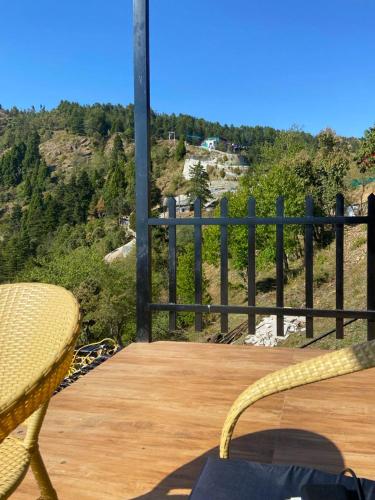 a wooden deck with a chair and a view of a hill at The Kiana's in Mussoorie