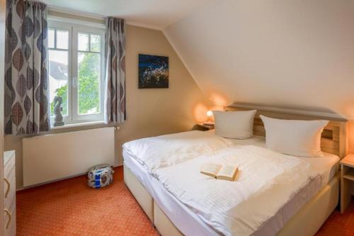 a bedroom with a bed with a book on it at Ostseeferienpark Seepferdchen direkt an der Ostsee - perfekt für Familien in Nienhagen