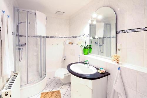 a white bathroom with a sink and a shower at Ostseeferienpark Seepferdchen direkt an der Ostsee - perfekt für Familien in Nienhagen