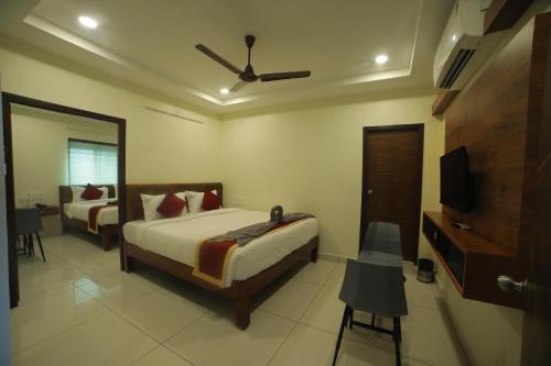 HOTEL ROI INN في تيروباتي: غرفة نوم بسريرين وتلفزيون بشاشة مسطحة