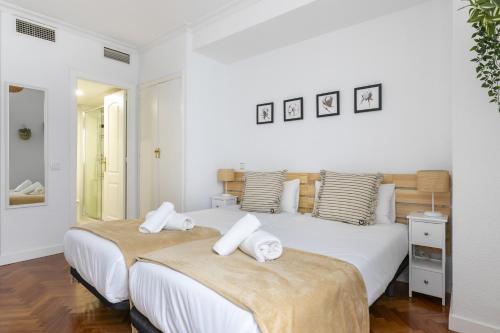2 camas en un dormitorio con paredes blancas y suelo de madera en Piso luminoso con balcones frente Parque Retiro en Madrid