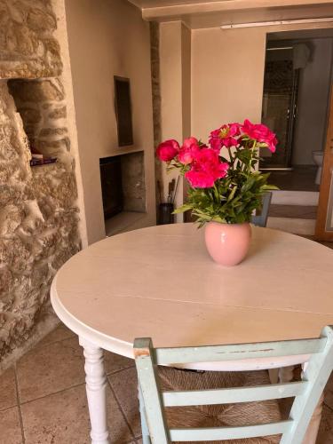un vase avec des fleurs rouges assis sur une table dans l'établissement Domaine de Cruvelet Petit gite, à Trigance