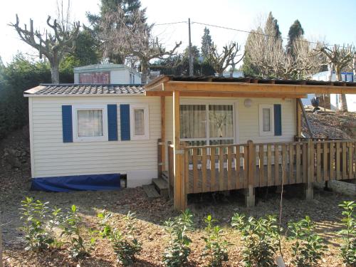 a small white house with a wooden deck at Camping La Douce Ardèche in Désaignes