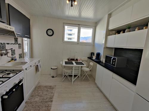 une cuisine avec des armoires blanches et une table à l'intérieur dans l'établissement Appartement T3 à Annecy, à Annecy