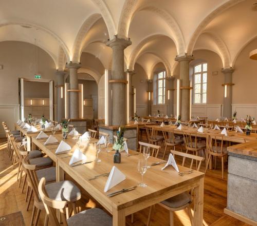 une grande chambre avec de longues tables et chaises dans l'établissement Hotel Kloster Holzen, à Allmannshofen