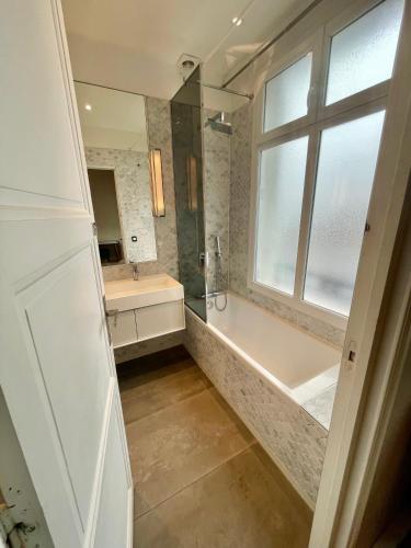 une salle de bain avec une baignoire, un lavabo et une fenêtre dans l'établissement Luxury apartment Times Square district, à Paris