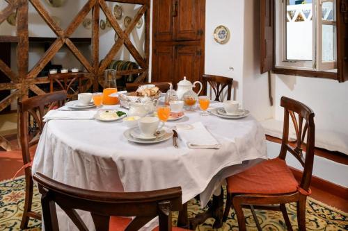 a table with a white table cloth on it with orange juice at Casa De Santiago in Santiago do Cacém