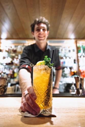 a man sitting at a counter holding a drink at Hotel Isolabella Wellness in Fiera di Primiero