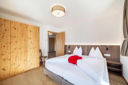 a bedroom with a white bed with a red blanket on it at Flatschhof - Apartment Vermoi in Kastelbell-Tschars