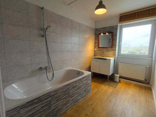 ein Bad mit einer Badewanne und einem Fenster in der Unterkunft gite pierre percée bord de Loire proche Nantes in Divatte sur Loire