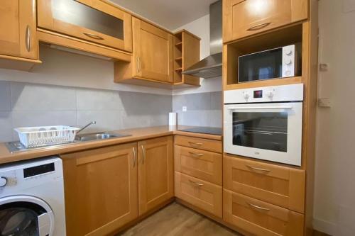 une cuisine avec des armoires en bois et une laveuse et une sécheuse dans l'établissement L'idéal - HyperCentre - 3CH - MyraConciergerie, à Pau