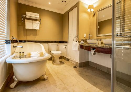 a bathroom with a tub and two sinks and a toilet at Hemingways Hotel in East London
