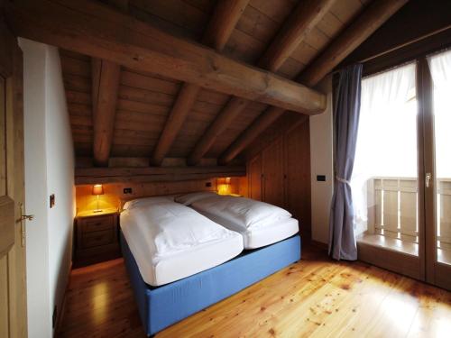 a bed in a room with a large window at Appartamenti Home Service in Arabba
