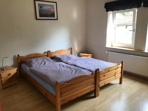 a wooden bed in a bedroom with a window at Ferienwohnung Zum Wilden Wein in Uslar