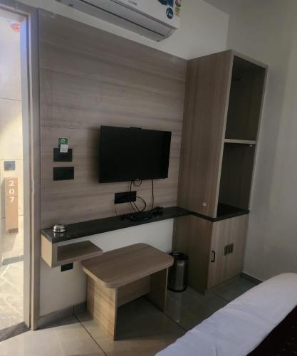 a room with a tv and a desk with a bench at Hotel Lee Pride in Anand