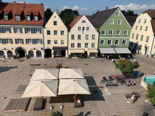 un groupe de bâtiments avec une cour avec un parasol dans l'établissement Ferienwohnung "beim Schrimpf", à Schongau