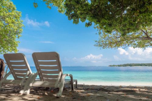 two chairs sitting on a beach near the water at Thundi Village & Spa in Maalhos