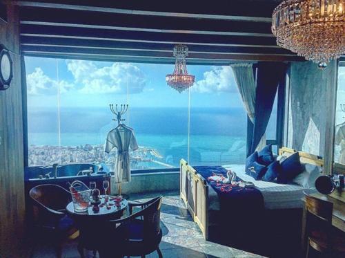 a bedroom with a bed and a table and a large window at Bay Lodge Boutique Hotel in Jounieh