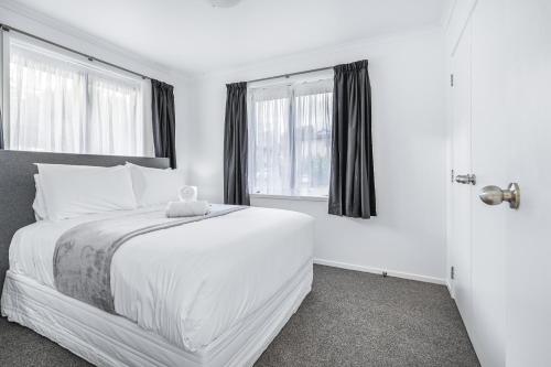 a white bedroom with a bed and two windows at Park Scenery, Proximity and Value - By KOSH BNB in Hamilton