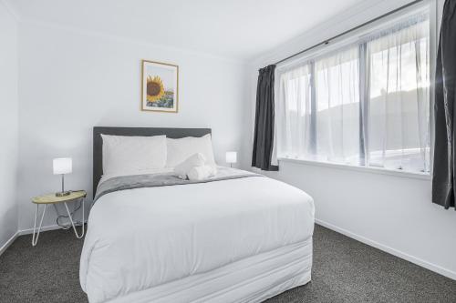 a white bedroom with a large bed and a window at Park Scenery, Proximity and Value - By KOSH BNB in Hamilton
