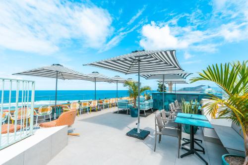 a patio with tables and chairs and umbrellas at Occidental Las Canteras in Las Palmas de Gran Canaria