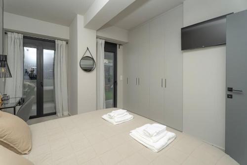 Un dormitorio blanco con dos toallas en una cama. en Speiō Luxury House, en Heraclión