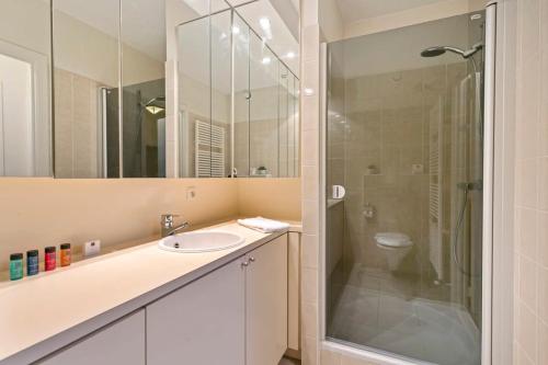 a bathroom with a sink and a glass shower at Knokke La Douce - Cozy apartment with side sea-view at only 50 meters from beach in Knokke-Heist